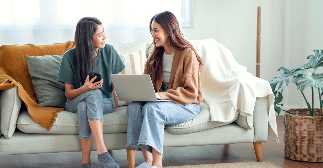 Two young woman sitting on a couch and chatting about the differences between Swiss German and Standard German