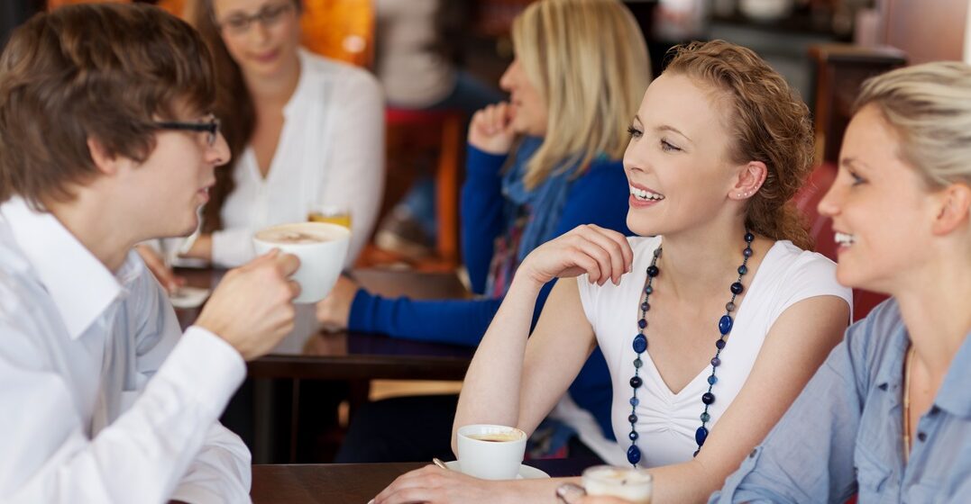 Three,Young,Friends,Having,Coffee,Together,In,A,Cafe,Seated