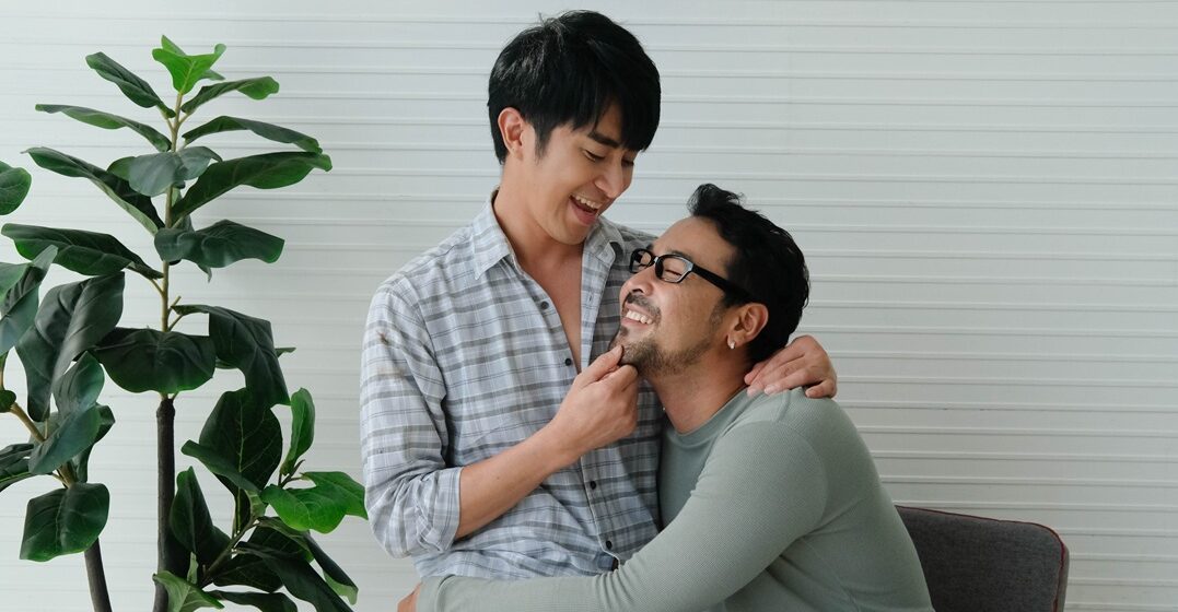 two queer men hugging each other, while one of them sits on the laps of the other and tells him I love you in Italian