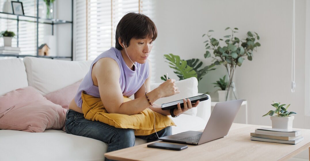 person sitting on the couch, with a tablet in their hand while they note down the adjectives in Italian