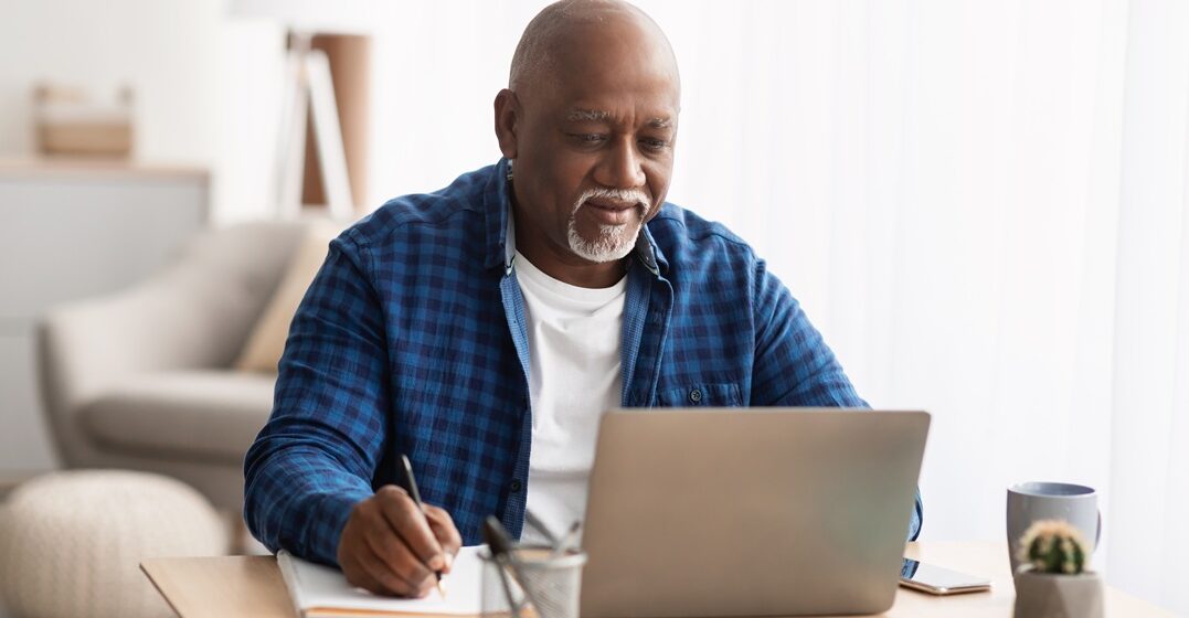 Black man, sitting at his desk and taking notes on how the essere conjugation works in Italian