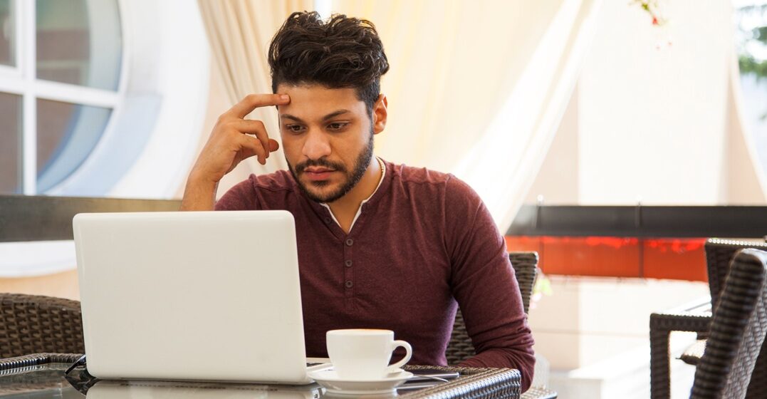 young man at his desk, learning on his laptop and wondering how long does it take to learn Italian