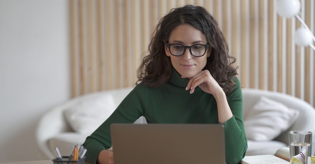 young dark-haired woman, studying Italian articles at her desk on a laptop