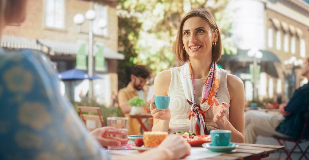 young women having a conversation using italian phrases sitting at a bar in Italy and sipping coffee and eating pastries.