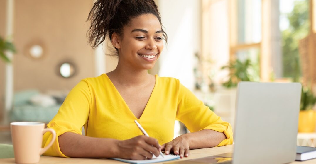 smiling girl sitting at her desk taking down notes on passato prossimo