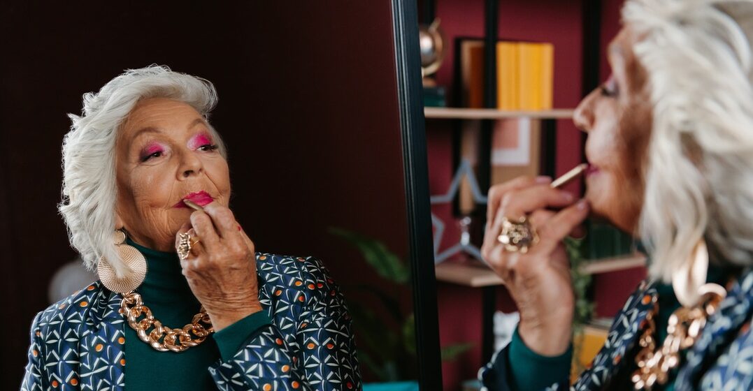 elderly woman making up in front of a mirror as a metaphor for reflexive verbs in Italian