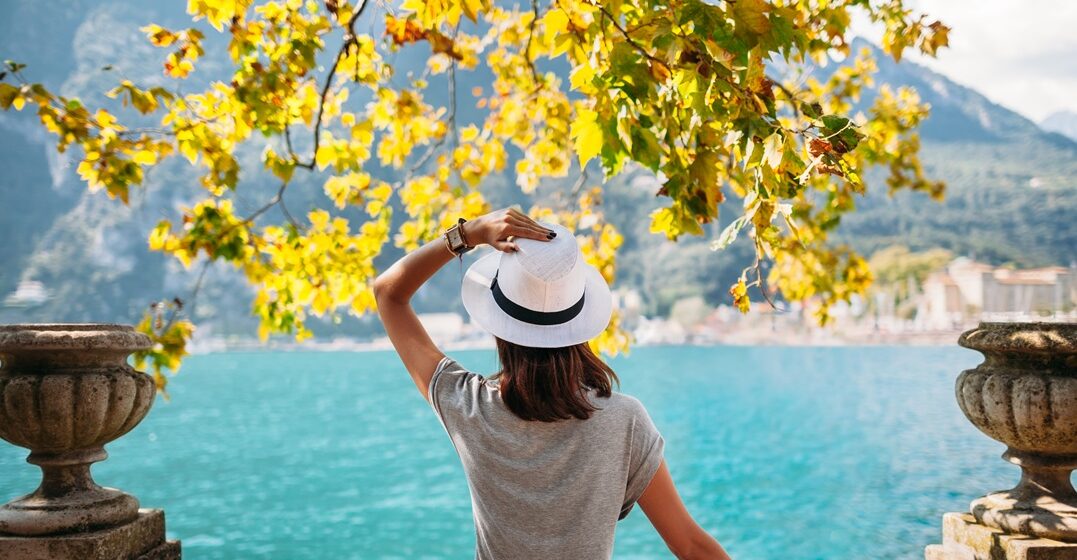 young woman showing her back to the camera and admiring a lake in and enjoying the seasons in Italy