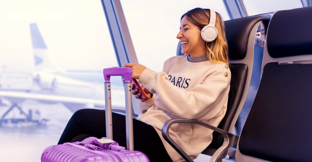 Woman sitting at an airport listening to a French podcast