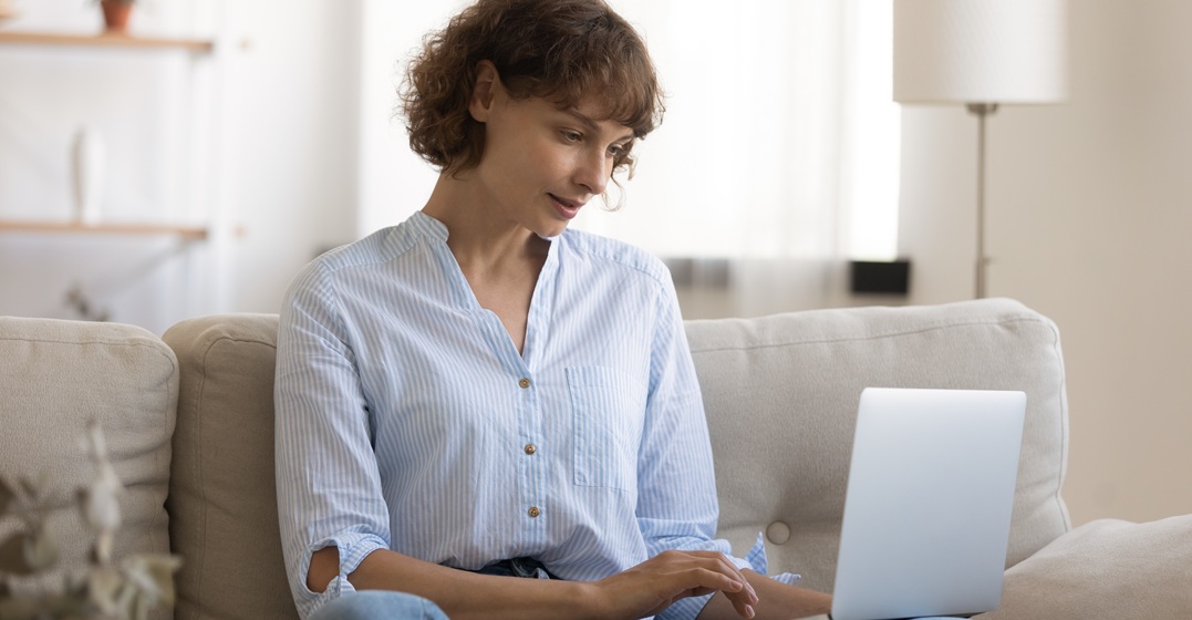 Woman sitting on a couch with her laptop writing a French cover letter