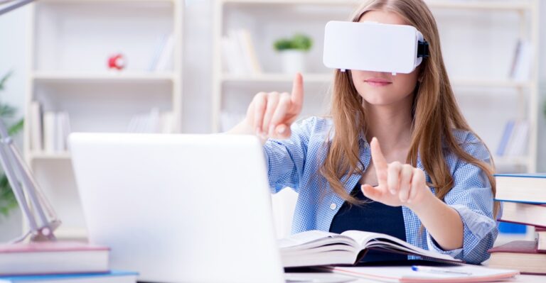 Junge Studentin sitzt an einem Platop und trägt eine VR Brille, was ihr beim Deutschlernen hilft