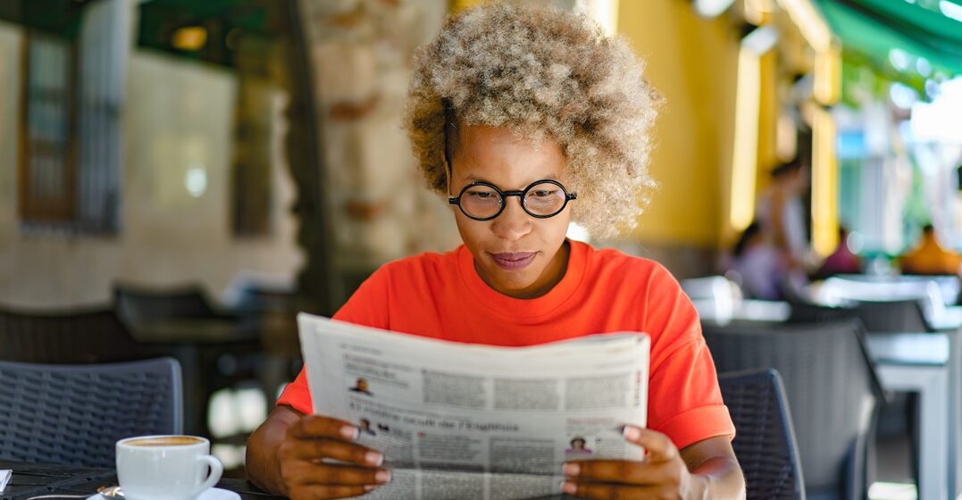 Middle aged woman reading some easy German news at her breakfast table