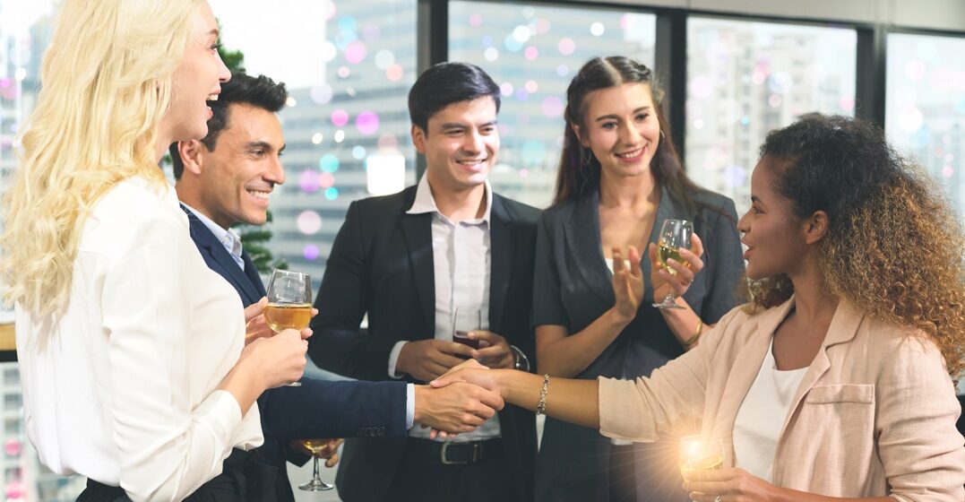 Group of people having adrink and surprise at hearing one female coworker introduce herself in German