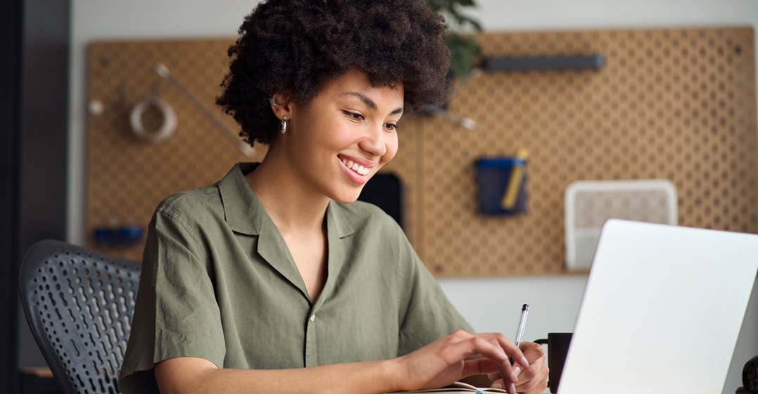 Eine afroamerikanische Frau sitzt an ihrem Laptop und lernt Wortverbindungen