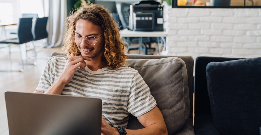 young hipster man sitting on an armchair and learning on his laptop with Lingoda the when to use als or wenn in German