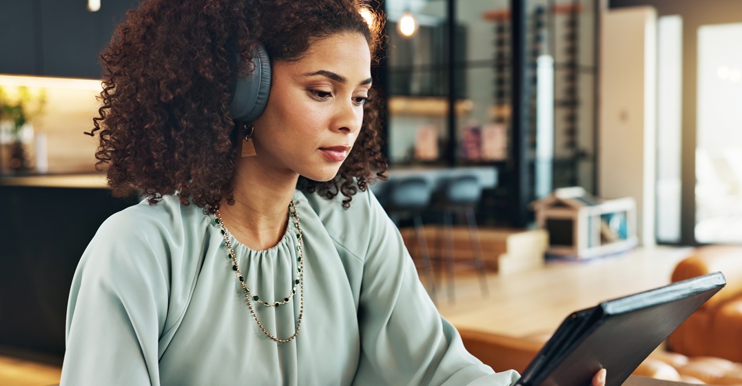 Woman with headphones holding a tablet where she learns the avoir conjugation