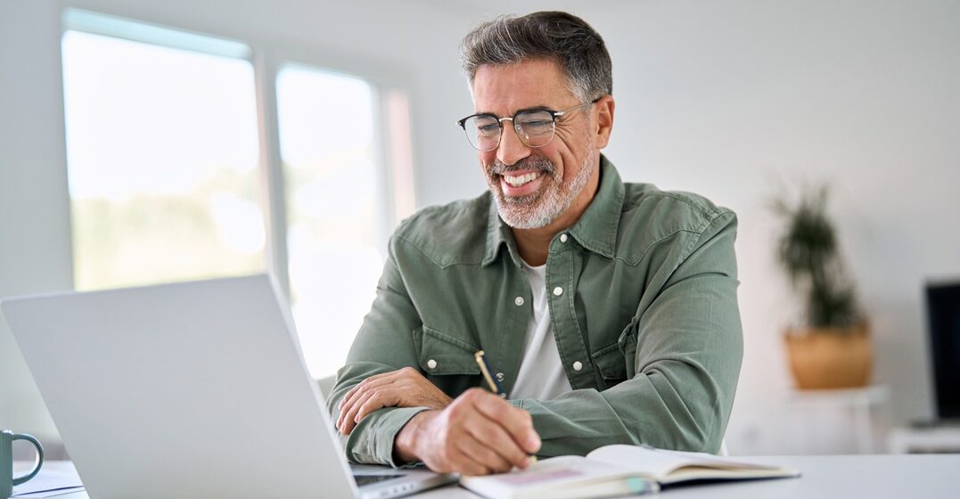Older man sitting at his desk learning on a laptop the indefinite articles in german