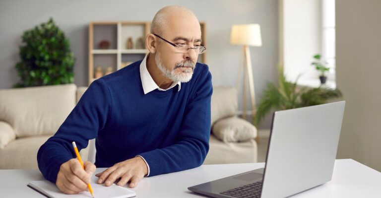 Senior man, studying at his desk the indirect questions in German with Lingoda