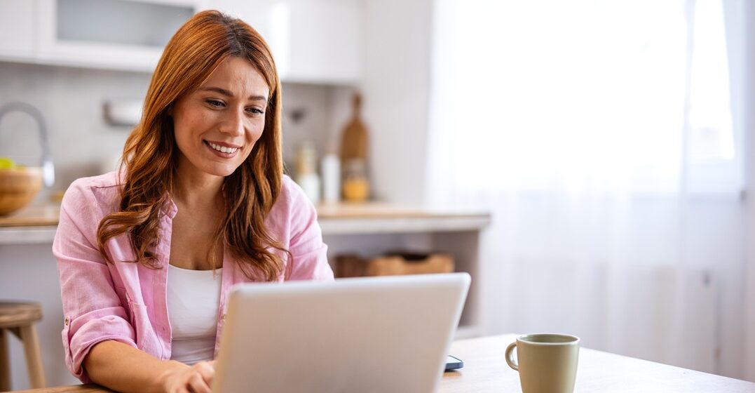 Young woman sitting at her desk with her laptop, learning the fahren conjugation in German