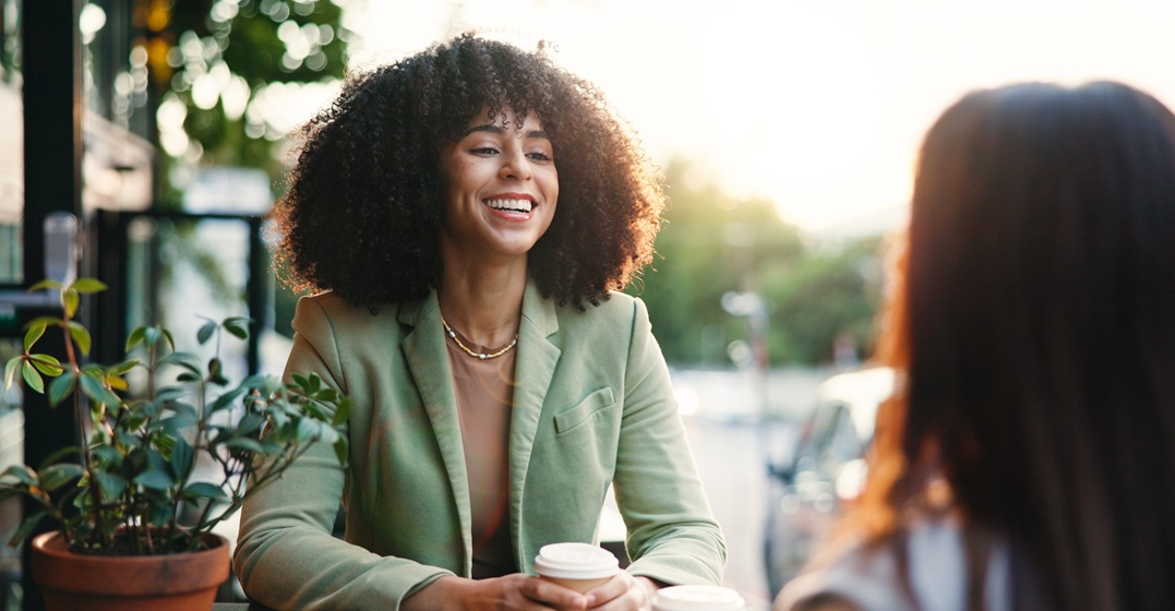 Eine junge afroamerikanische Frau sitzt im Café mit einer Freundin und übt Konnektoren