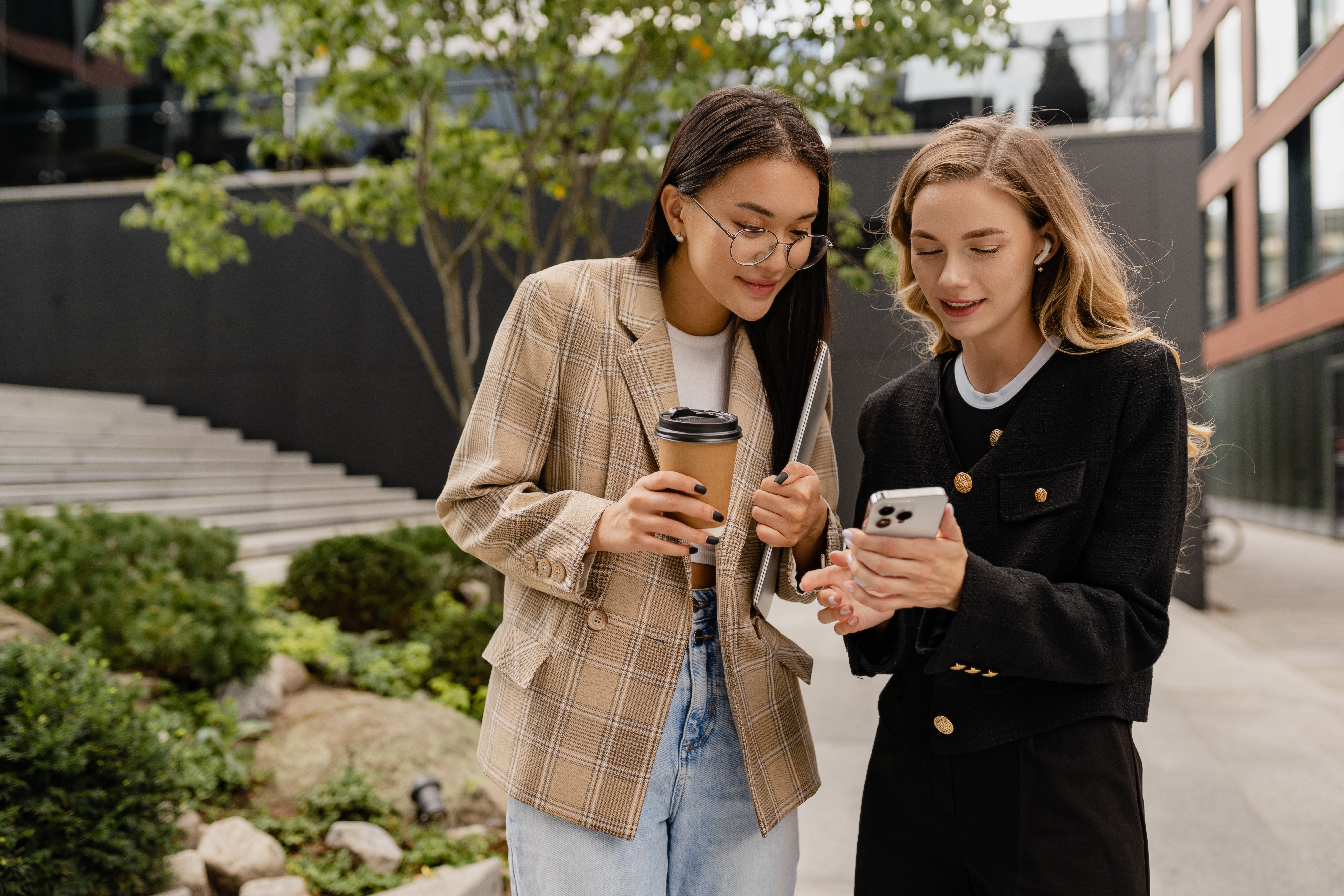Two young female students look at a phone to learn the prepositions of movement