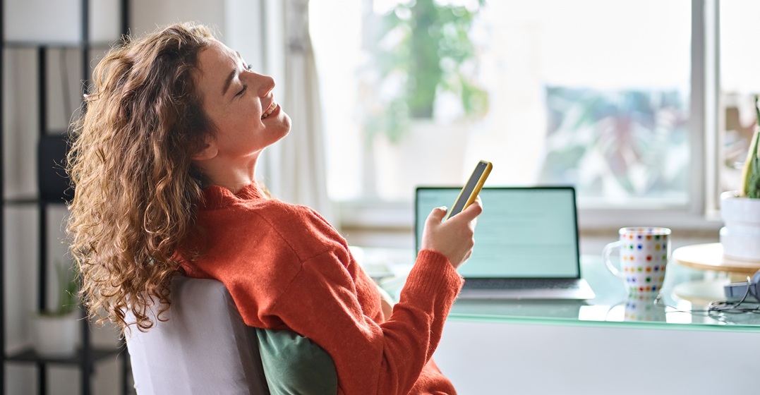 Junge lächenlde Frau im Homeoffice genießt ihre work-life balance