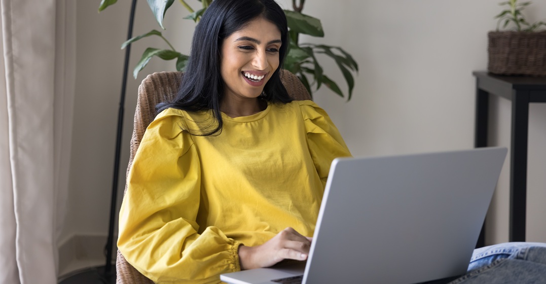 Eine junge Frau sitzt an ihrem Laptop und schreibt ein Bewerbungsschreiben auf Deutsch
