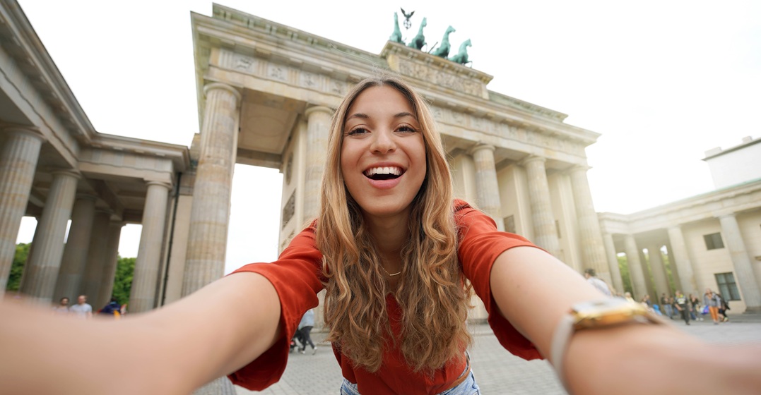 Young woman looking straight into the camera in front of Brandenburger Tor as an expat adjusting to German culture
