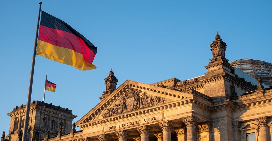 Image of the Bundestag at sunset with a couple of German flags waving to honour the National german language day