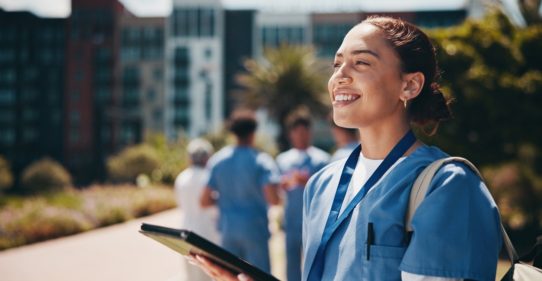 Close up of a happy woman looking towards teh sun as she's holding a scholarship to study in Germany