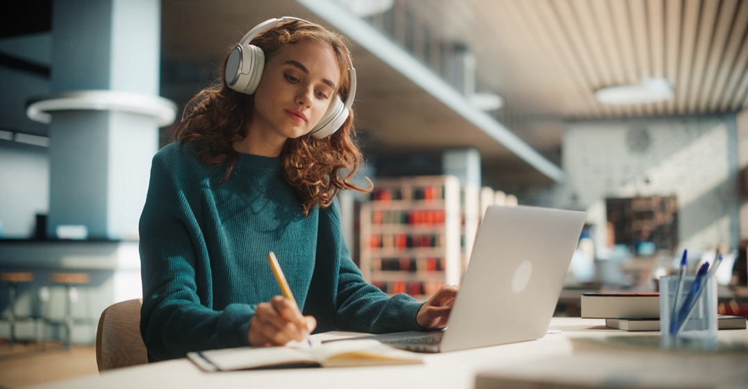 Konzentrierte Frau am Lapto mit Kopfhörern lernt alle deutschen Wortarten