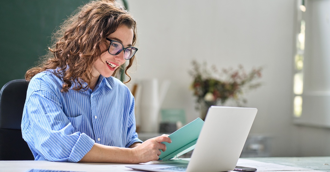Junge Frau am Laptop sucht einen der besten Online Englischkurse raus