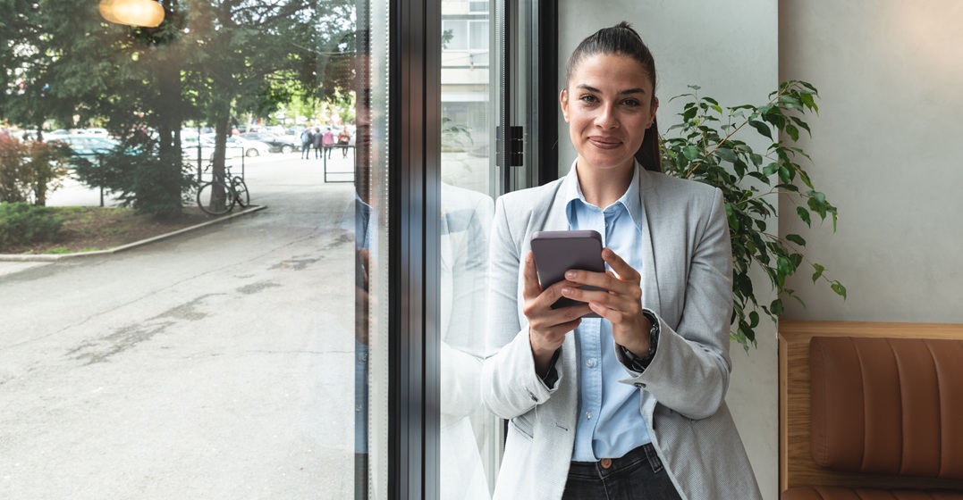 Business woman expat holding her phone thinking about confidence barriers expats face