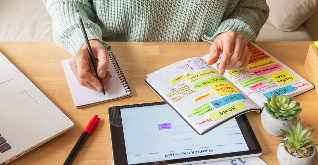 Organised woman reading in her calendar and noting down her language learning goals