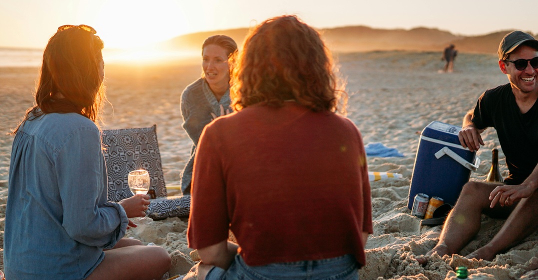 Eine Gruppe Menschen am Strand im Urlaub mit sprachlichen Unsicherheiten der Landessprache